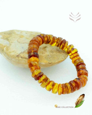 Yellow amber bracelet resting on a stone.