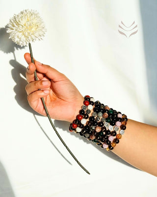 Multiple crystal bracelets on arm with flower