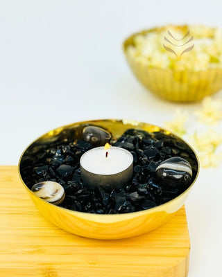 Gold bowl with candle and black stones for negativity protection